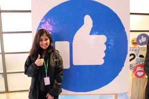 Afra Ansaria gives a thumbs-up in front of a giant Facebook "Like" button