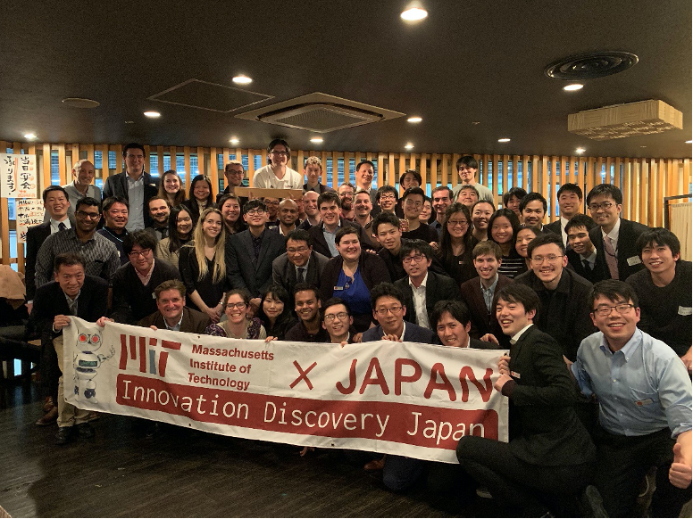 A large crowd of students, staff, and others gather behind the IDJ banner in a bar