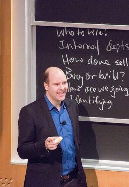 Bruce Cameron, standing in front of a chalkboard covered in writing