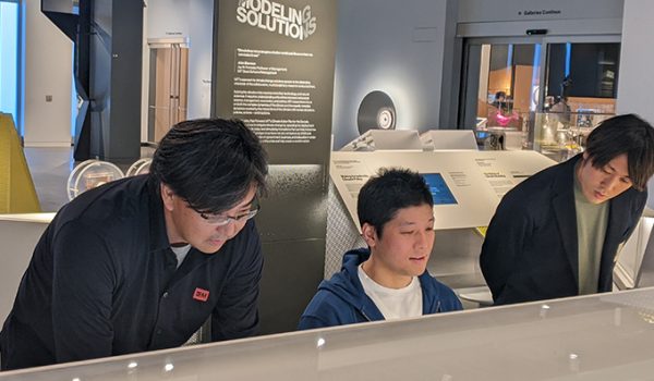 Three men interact with a museum exhibit.