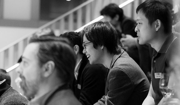 A black-and-white photo of students seen in profile, listening to an unseen speaker.