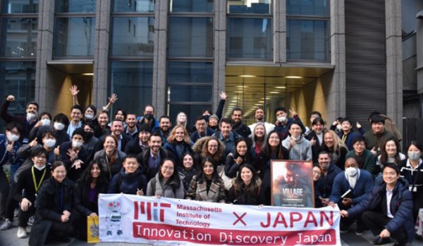 Students and staff gathered in front of an office building holding a banner reading "MIT x Japan Innovation Discovery Japan"