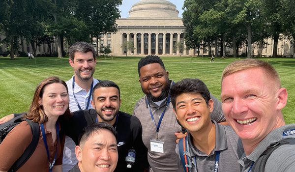 A group of students smiling in front of the MIT Dome.