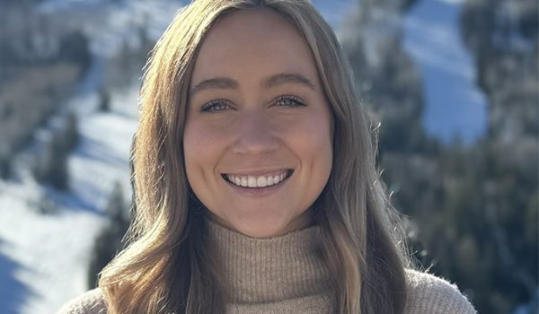 Headshot of Caroline Vincent, a blonde woman wearing an oatmeal-colored turtleneck. In the background is a snowy hill with evergreen trees.